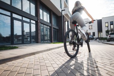 Spor giysiler ve spor ayakkabılar giyen genç bir kadının temiz havada bisiklet sürüşüne yakından bakın. Güçlü kadın bacaklarına odaklan. Genç insanda aktif yaşam biçimleri.