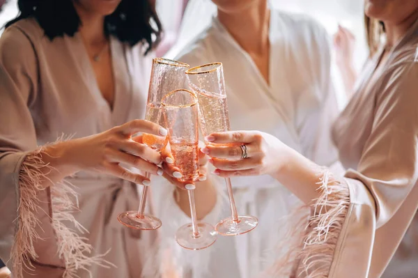 Close-up view of female hands holding glasses with vine or champagne. Bridesmaids and bride celebrate Wedding day