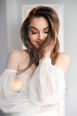 Beyaz elbiseli romantik güzel gelin gözleri kapalı poz veriyor. Gri arka planda esmer gelinin güzel portresi 