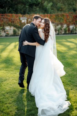 Back view of bride and groom embracing and posing on a background of garden. Loving couple together. Stock photo 