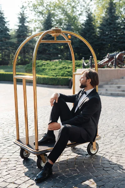 Stylish Handsome Groom Wearing Elegant Suit Sitting Hotel Luggage Trolley — Stock Photo, Image