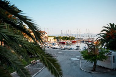 Bir sürü demirli gemiyle küçük iskelenin yakınındaki terk edilmiş asfalt sokak manzarası. Hırvatistan 'ın Supetar kentinin resimli manzarası. Mimarlık ve yaz mevsimi kavramı.