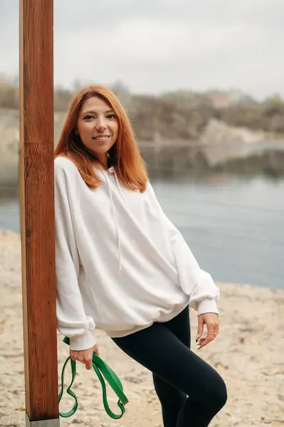 Nehrin Arka Planında Beyaz Kazaklı Siyah Taytlı Mutlu Kızıl Saçlı — Stok fotoğraf