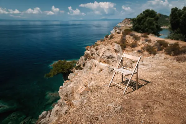 免费的空木椅矗立在岩石悬崖上 海景秀丽 希腊阳光灿烂的夏日 — 图库照片