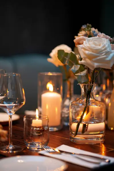 Mumlar ve çiçeklerle donuk bir ortamda şık bir masa..