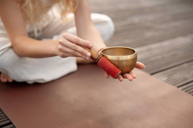 Elinde yoga minderinde tokmakla Tibet şarkı kasesi tutan bir adam..