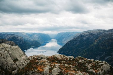 Norveç 'teki Lysefjord manzarası bulutlu bir gökyüzünün altında kayalık dağlarla çevrili..