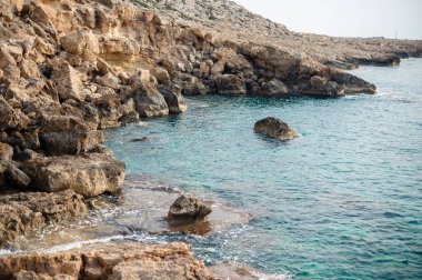 Berrak turkuaz suyu ve engebeli uçurumları olan kayalık kıyı şeridi..