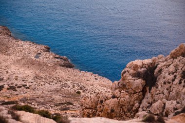 Sert kayalıkları ve derin mavi denizi olan kayalık sahil şeridi..