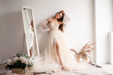 Gelin sabah aynanın yanında toplanır. Profesyonel fotoğraf stüdyosunda şık şampanyalı gelinlik giyen bir kadın. 