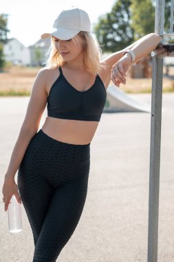 Yaz boyunca sabah antrenmanından sonra dinlenirken stadyumda ayakta duran ve dişlek bir şekilde gülümseyen kadının dikey görüntüsü. Sokak çalışması konsepti