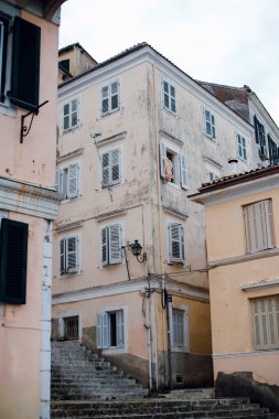 Yıpranmış, pastel renkli bir bina. Bir Avrupa kasabasının pencereleri panjurlu..