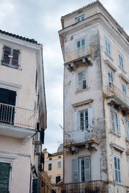 Bulutlu bir gökyüzünün altında yıpranmış cepheleri ve balkonları olan eski Avrupa binaları.