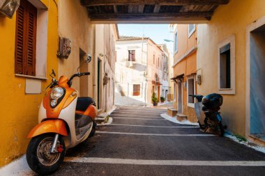 Akdeniz 'de renkli binalar ve park etmiş scooterlarla dolu dar bir ara sokak..