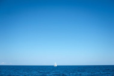 Uçsuz bucaksız, sakin bir okyanusta, masmavi gökyüzünün altında yalnız bir yelkenli..
