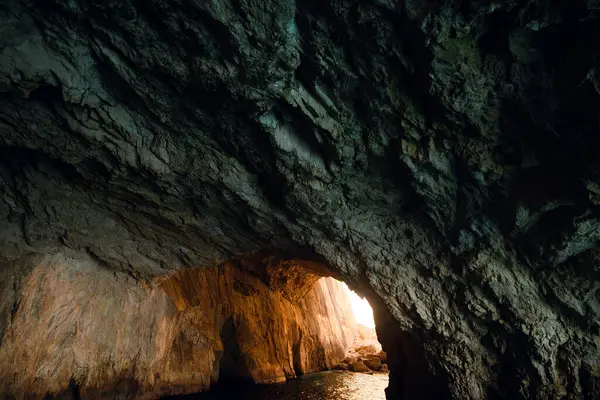Kayalık duvarları ve gün ışığına açılan loş bir mağara..