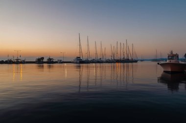 Gün batımında sakin bir marina ve sakin sulara bakan yelkenli tekneleri..