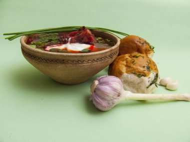 Tabağında donut olan geleneksel Ukrayna borsası. Borş zengin kırmızı bir renge ve ekşi krema ile süslenmiş iştah açıcı bir görünüme sahiptir. Yakınlarda sarımsaklı çörekler var..