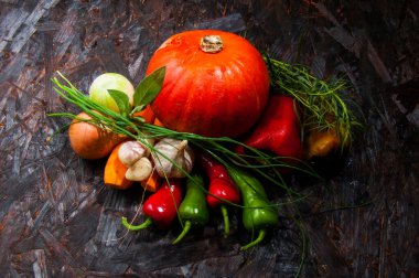 İçten bir yemek için taze sebze kompozisyonu: balkabağı, biber, soğan, sarımsak ve bitkiler. Sıcak renkler ve doğal dokular ev yapımı sıcak bir yemeğe işaret ediyor..