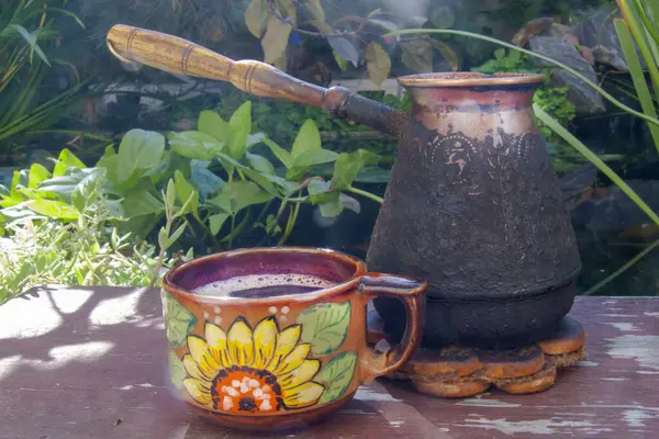 Ahşap bir masada kahveyle hayat. Ayçiçeği desenli bir kap ve cezalandır. Sıcak atmosfer, güneş ışığı, detaylara odaklan.