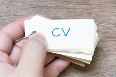 Ahşap zemin üzerinde CV (müfredat vitae kısaltması) ile el yazısı içeren el bilgisayarı flaş kartı