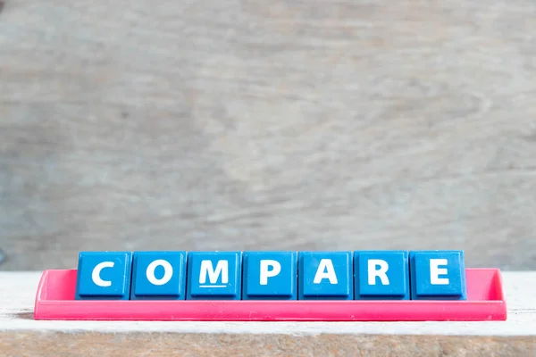 stock image Tile alphabet letter with word compare in red color rack on wood background