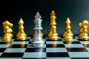 Gümüş kral satranç taşı siyah arka planda başka bir altın takımla karşı karşıya (liderlik kavramı, sorun veya kriz durumu)