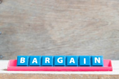 Ahşap arka planda kırmızı rafta kelime indirimi içeren döşeme alfabesi harfi