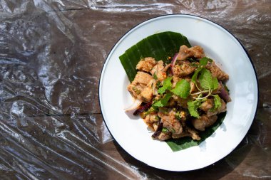 Tayland yemeği baharatlı ızgara domuz salatası ve ahşap arka planda beyaz tabak.