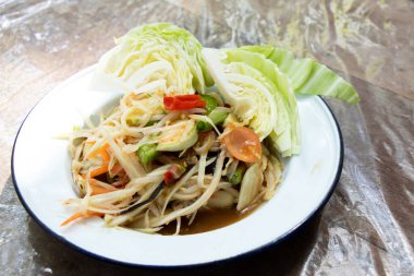 Tahta masadaki beyaz tabakta Tayland papayası salatası (Somtum)