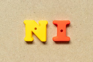 Plastic alphabet letter in word NI (Abbreviation of net income, no idea, national insurance or nursing informatics) on wood background
