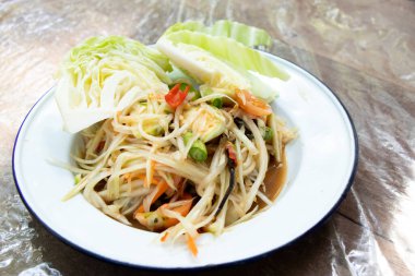 Tahta masadaki beyaz tabakta Tayland papayası salatası (Somtum)