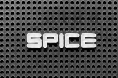 White alphabet letter in word spice on black pegboard background