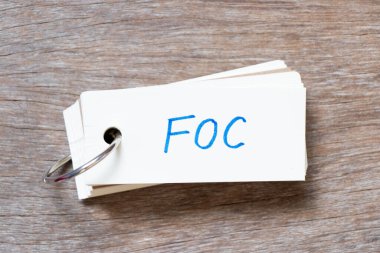 Flash card with handwriting in word FOC (Abbreviation of Free of charge) on wood background