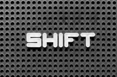 White alphabet letter in word shift on black pegboard background