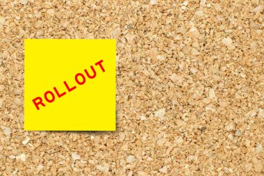 Yellow note paper with word rollout on cork board background with copy space