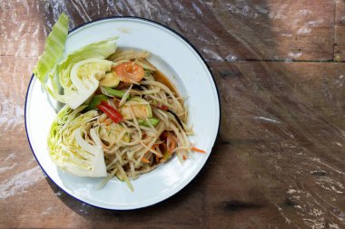 Tahta masadaki beyaz tabakta Tayland papayası salatası (Somtum)