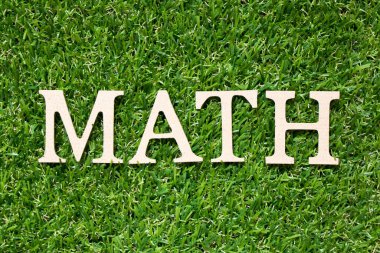 Tahta alfabe harfi matematikte yapay yeşil çimen arkaplanı üzerine