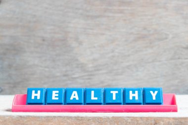 Ahşap arka planda kırmızı raflarda sağlıklı sözcüğüyle harf döşemesi