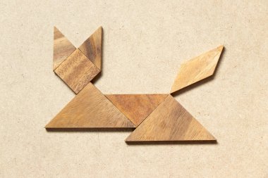 Kedi otururken ahşap bir tangram ya da ahşap arka planda yatarken