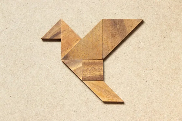 Wooden tangram in flying bird shape on wood background