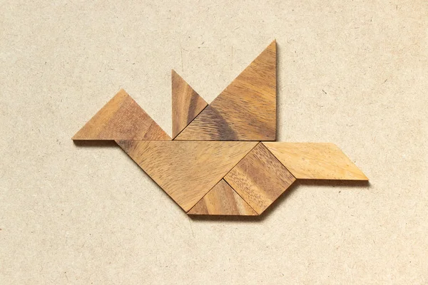 Wooden tangram in flying bird shape on wood background