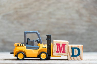 Toy forklift harf bloğu M (tıp doktorunun kısaltması veya genel müdür) ahşap arka planda)