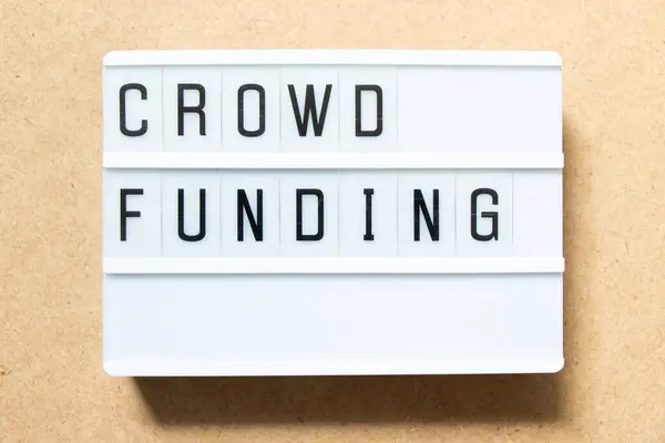 Lightbox with word crowd funding on wood background