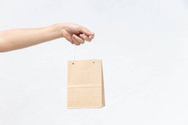 Hand of business woman hold brown paper shopping bag on white concrete background