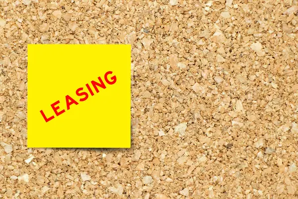 stock image Yellow note paper with word leasing on cork board background with copy space