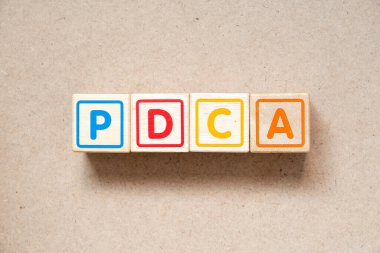 Tahta arkaplan üzerindeki PDCA harfli alfabe harf bloğu (planın kısaltması kontrol eylemi)