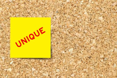 Mantar kaplama arka planında özgün sözcüğe sahip sarı not kağıdı kopyalama alanı ile