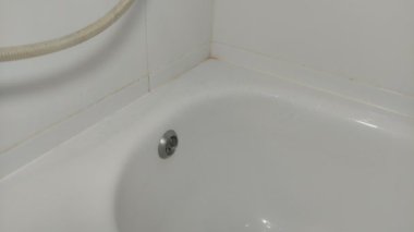 Hizmetçi banyoda banyo küvetini kimyasallarla yıkıyor.