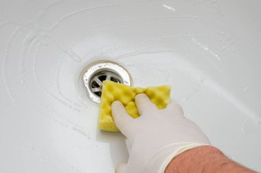 Hizmetçi banyoda banyo küvetini kimyasallarla yıkıyor.